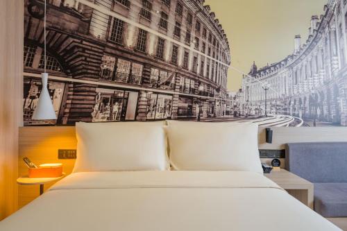 a bedroom with a white bed in front of buildings at 亚轻x酒店上海同济医院新村路地铁站店 in Shanghai