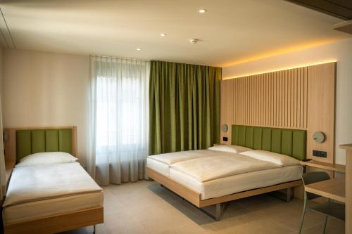 two beds in a hotel room with green curtains at Hôtel le Square in Geneva