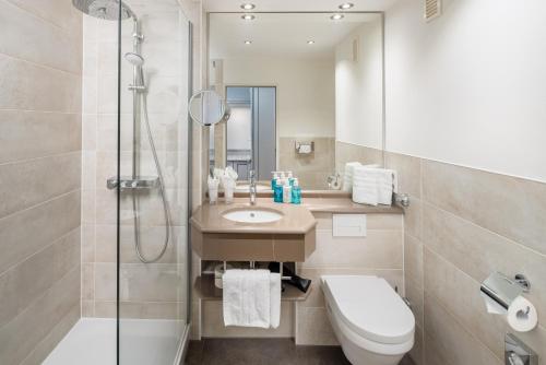 a bathroom with a sink and a toilet and a shower at Hotel Wiking Sylt in Westerland
