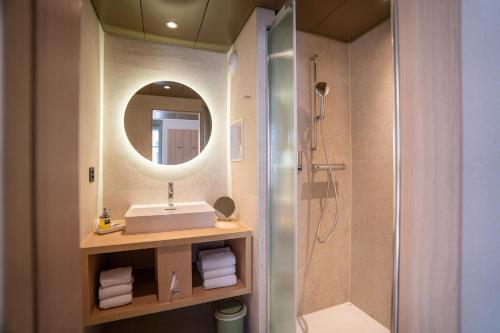 a bathroom with a sink and a shower with a mirror at Hôtel le Square in Geneva