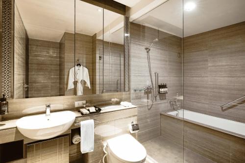 a bathroom with a sink and a toilet and a shower at Ascott Waterplace Surabaya in Surabaya