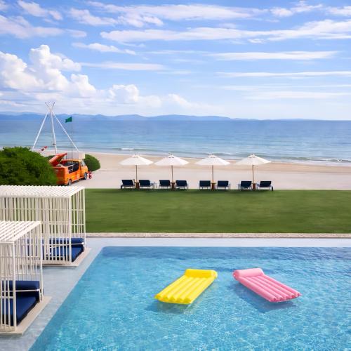 a swimming pool with two slides in front of a beach at Veranda Residence Pattaya in Na Jomtien