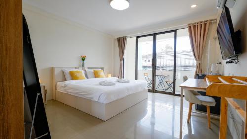 a bedroom with a white bed and a balcony at Three Monkeys Chaweng Beach in Chaweng