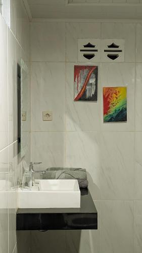 a white bathroom with a sink and paintings on the wall at Villa de Gema in Selabintana