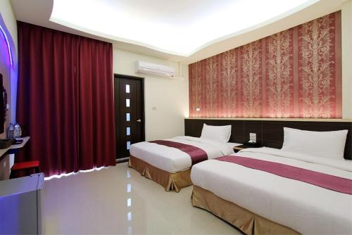 two beds in a hotel room with red curtains at Blue Ocean Stars in Taitung City