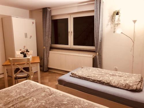 a bedroom with two beds and a table and a window at Pension Nazli Lübeck in Lübeck