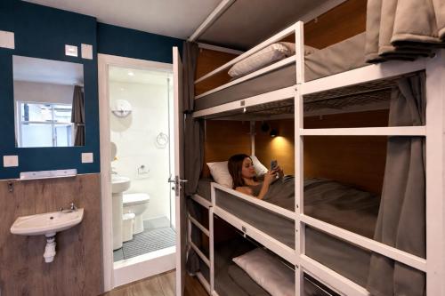 a woman is looking at her cell phone in a bunk bed at Smart Camden Inn in London