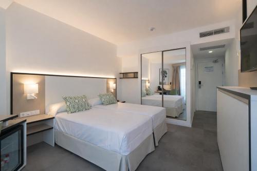 a bedroom with a large white bed and a mirror at Medplaya Hotel Regente in Benidorm
