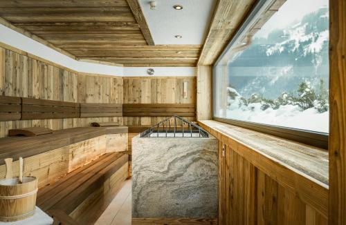 a sauna with a large window and a tub at Alpenresidenz-Sonnwend - Wellness Apartments nahe Zillertal Arena in Zell am Ziller