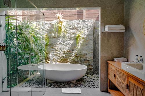 a bathroom with a tub and a glass shower at Goya Courtyard Ubud in Ubud