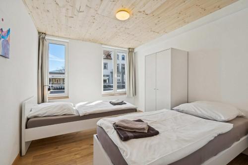 two beds in a room with two windows at FENUS SGT01 moderne Ferienwohnung in Grabs