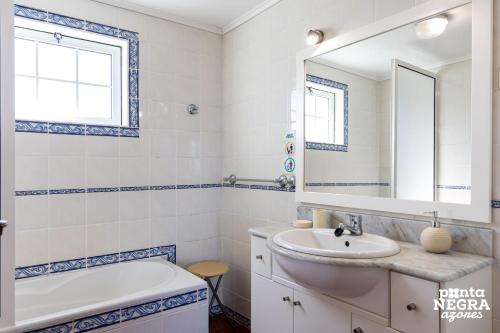 a bathroom with a sink and a tub and a mirror at Casa da Maresia by PontaNegraAzores in Biscoitos
