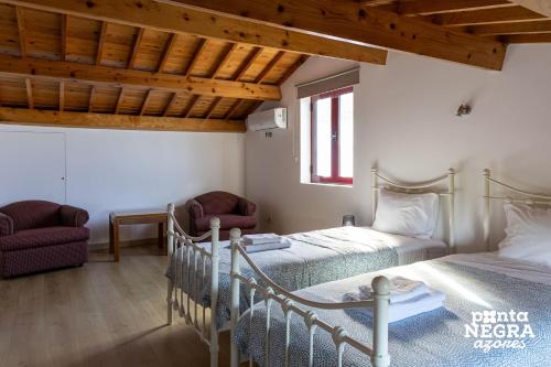 a bedroom with two beds and two chairs at The North House by Ponta Negra Azores in Biscoitos