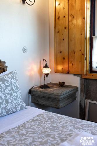 a bedroom with a bed and a lamp on a table at Casa da Hortênsia Roxa by Ponta Negra Azores in Praia da Vitória