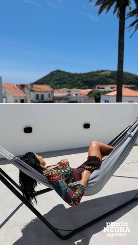 a woman laying in a hammock on a balcony at City House by PontaNegraAzores in Angra do Heroísmo