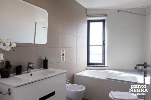 a white bathroom with a tub and a sink and a toilet at Casa Maré by PontaNegraAzores in Angra do Heroísmo