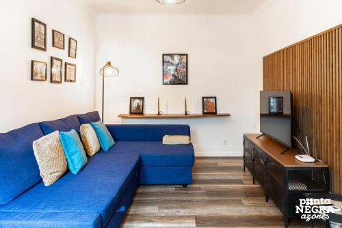 a living room with a blue couch and a tv at The Biscuit House by PontaNegraAzores in Praia da Vitória