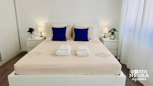 a white bed with blue pillows and towels on it at City House by PontaNegraAzores in Angra do Heroísmo