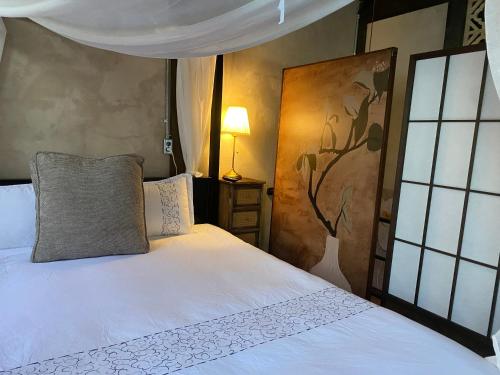 a bedroom with a white bed and a painting on the wall at Lane 82 Homestay in Chiayi City