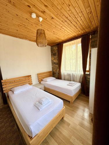 a bedroom with two beds and a wooden ceiling at Olympos Stone House in Kumluca