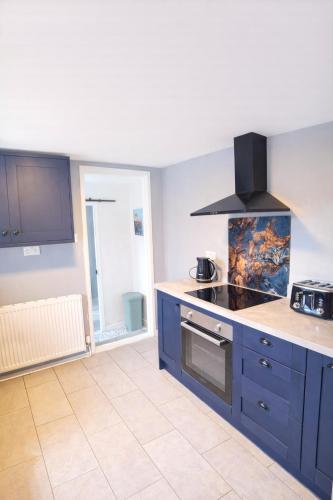 a kitchen with blue cabinets and a stove at Seaside Cambois Apartment in Cambois