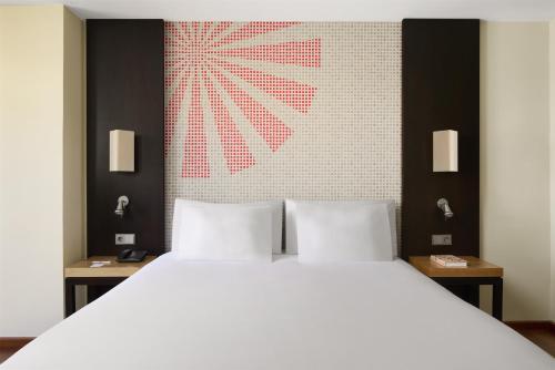 a bedroom with a large white bed and a wall at iStay by NH Ciudad de Valencia Hotel in Valencia