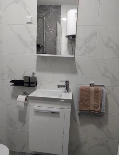 a white bathroom with a sink and a mirror at Studio Apartman Tara in Daruvar