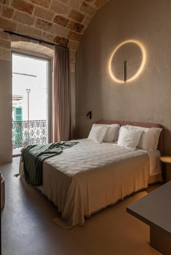 a bedroom with a large bed and a large window at Palazzo Cerere Boutique Hotel in Polignano a Mare