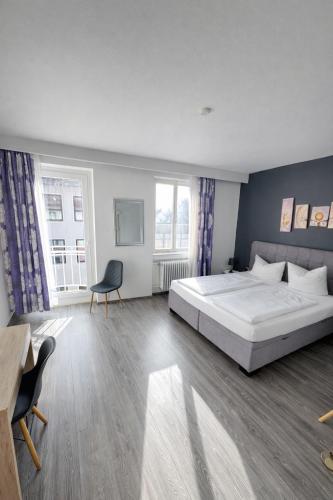 sypialnia z łóżkiem, biurkiem i dwoma oknami w obiekcie Hotel Brigach w mieście Villingen-Schwenningen