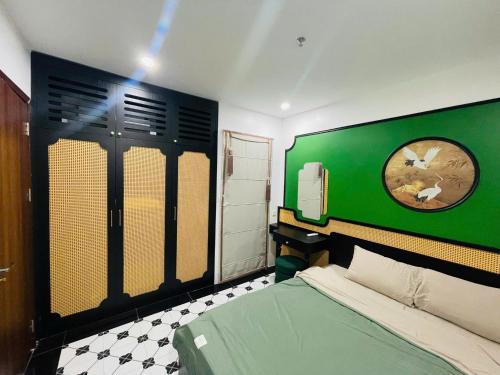 a bedroom with a green headboard and a clock on the wall at Green Park Lang Son Apartment in Lạng Sơn