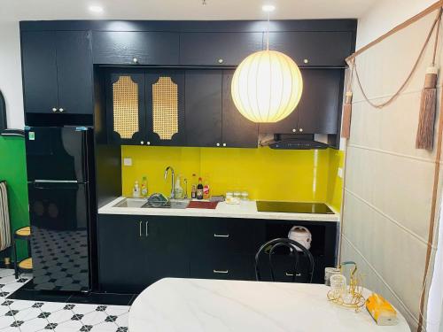 a kitchen with black cabinets and a yellow wall at Green Park Lang Son Apartment in Lạng Sơn