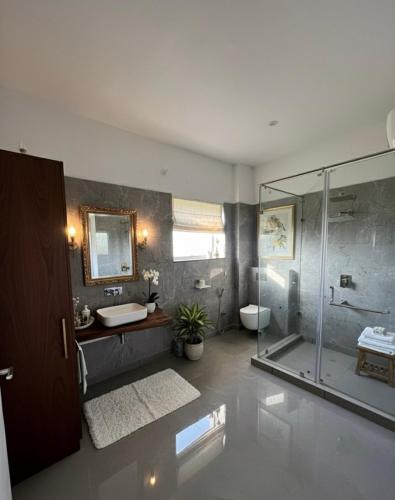 a bathroom with a glass shower and a sink at Privé Residence in Rāmnagar
