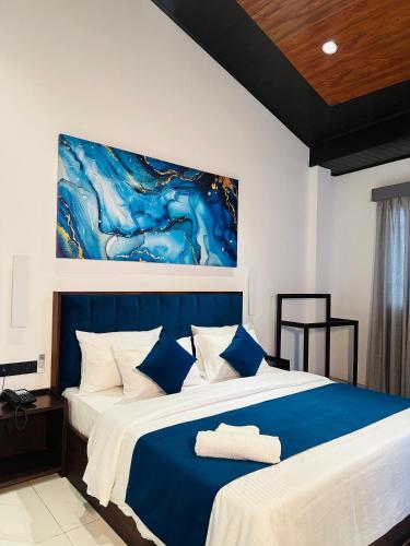 a bedroom with a blue and white bed with a painting on the wall at O2 Resort Welimada in Nugatalawa