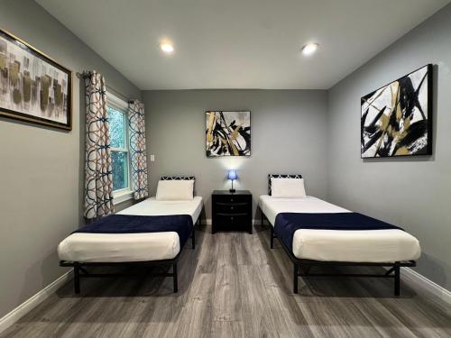 two beds in a room with two windows at Spacious 3 bedroom unit with backyard and parking just 10 minutes from Rodeo Dr and attractions! in Los Angeles