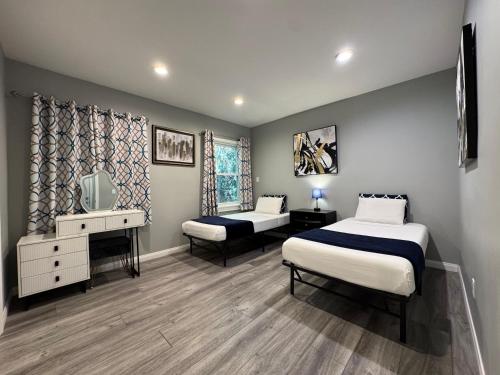 a bedroom with two beds and a desk and a tv at Spacious 3 bedroom unit with backyard and parking just 10 minutes from Rodeo Dr and attractions! in Los Angeles