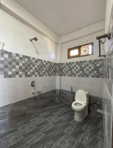 a bathroom with a toilet and a tiled floor at Cosy Crest in Banjār