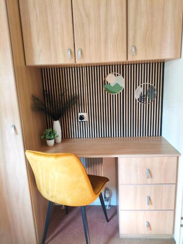 a desk with a yellow chair next to a cabinet at Odpocznij w Lesie in Biały Dwór