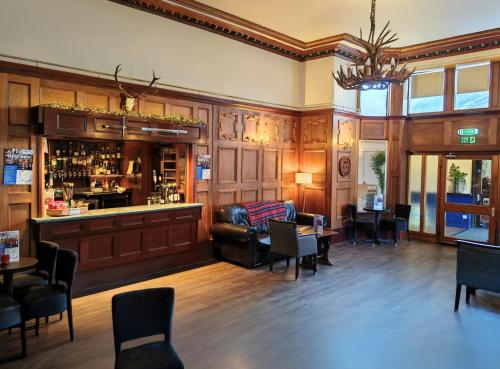 a restaurant with a bar with a couch and chairs at The Caledonian Claymore Hotel in Arrochar