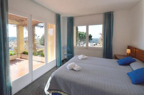 a bedroom with a large bed with blue curtains and windows at Quatre vents Ref 163 in Begur