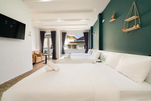 a large bedroom with white beds and a green wall at Gia Khanh Hotel in Da Lat