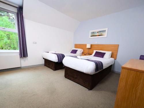 a bedroom with two beds and a window at The Caledonian Claymore Hotel in Arrochar