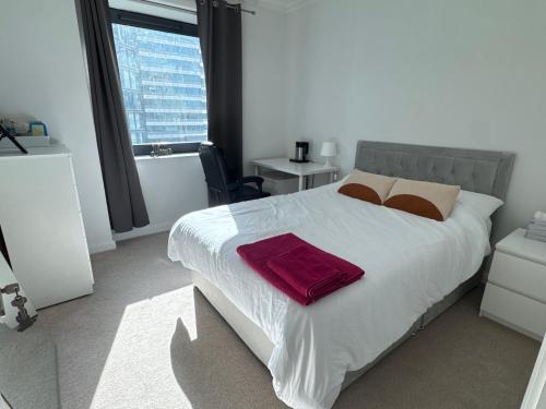 a bedroom with a large bed with a red towel on it at Canary Wharf-WOMEN Only-Private Double Room & Pool Gym in London