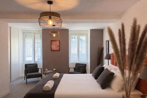 a bedroom with a large bed with two chairs at Flor du Mont Gîte in Pontorson