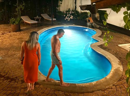 a man and a woman standing next to a swimming pool at Hanami House Boutique 4 Estrellas Valle del Jerte in Navaconcejo