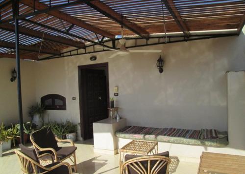 a patio with chairs and a bed in a room at Fayrouz Apartmernts in Luxor