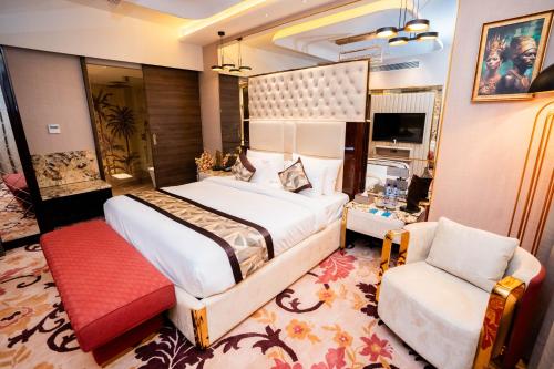 a bedroom with a large bed and a chair at La Belle - The Business Hotel in Lubumbashi