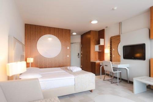 ein Schlafzimmer mit Bett, Schreibtisch und Fernseher in der Unterkunft Hotel Terme - Terme Čatež in Čatež ob Savi