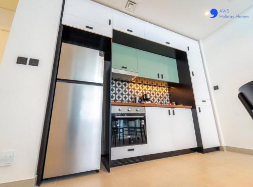 a kitchen with a stainless steel refrigerator in a room at AWS Holiday Homes - Stylish 2BR Apt at Dubai Hills in Dubai