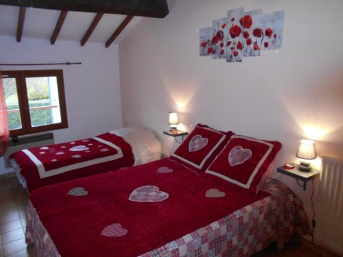une chambre avec deux lits avec des draps rouges et des coeurs dans l'établissement les Passerons, à Vaumeilh