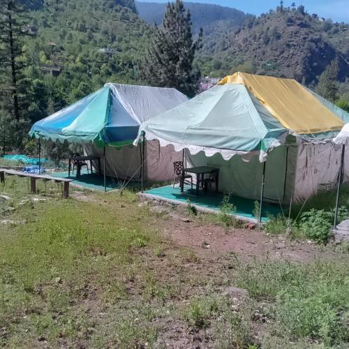 two tents in a field with mountains in the background at Shoolin camping in Jari